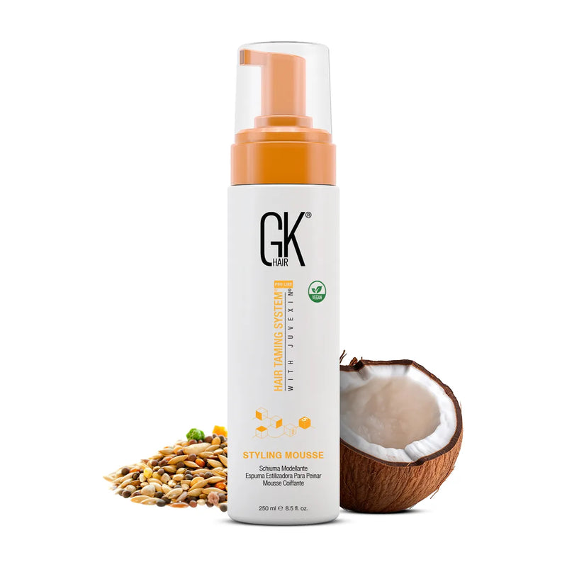 GK Hair Styling Mousse, 250 ml white pump bottle with orange collar, mixed seeds and half a coconut beside it
